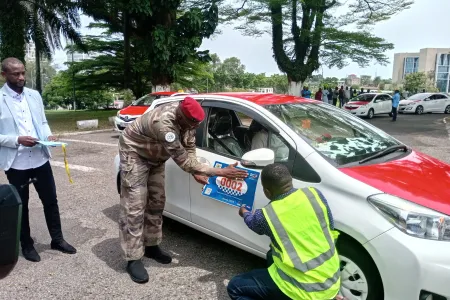 Le délégué spécial de Libreville procédant au collage symbolique de la vignette sur un taxi.